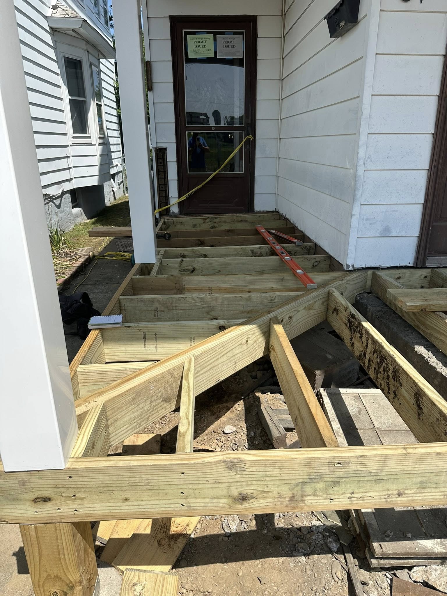 Completed concrete porch stairs and landing with attached wooden deck structure.